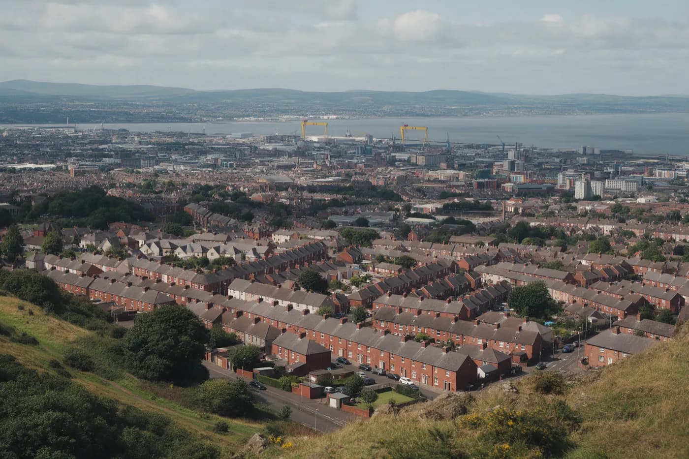 Belfast seen from Cave Hill: red brick terraced streets running down to Belfast Lough and the two shipyard cranes