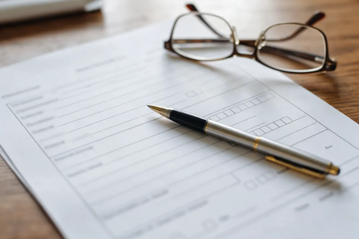 A pen and reading glasses resting on a printed form